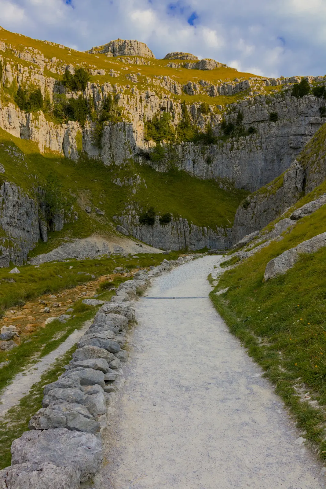 The footpath into Gordale Scar, running beside a dry stone wall below limestone cliffs