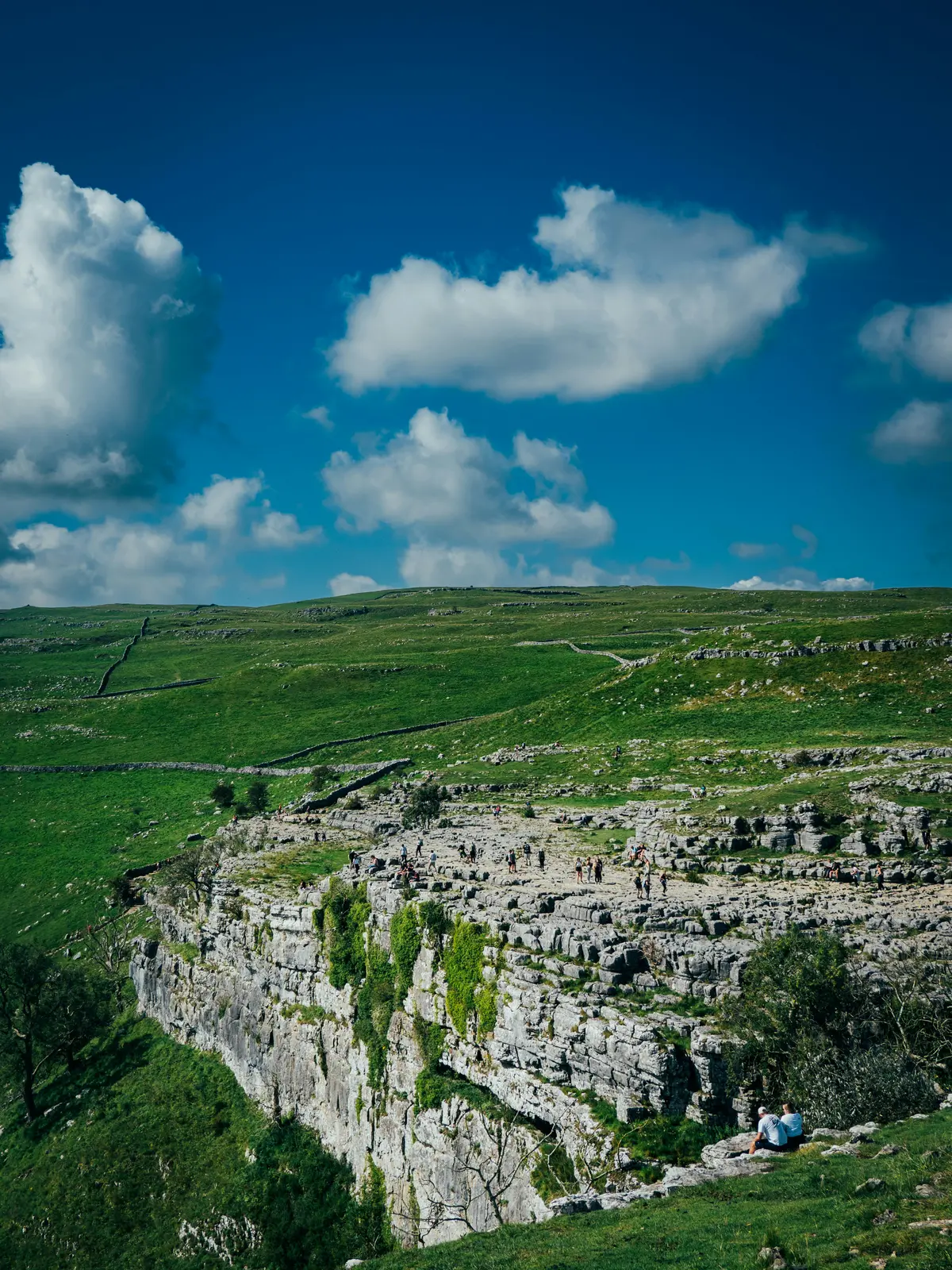 Visitors walking across the limestone pavement on top of Malham Cove